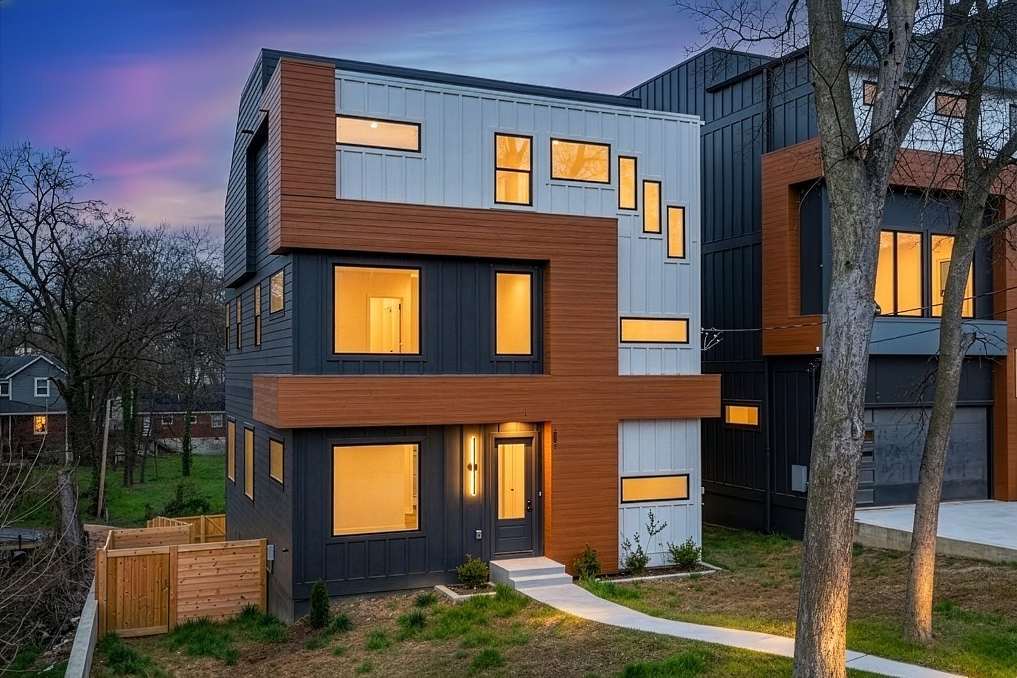 Front exterior of 1001 Glenview Drive, a new three story modern home with gray and wood tone siding, black framed windows, and a front walk, one of the East Nashville homes for sale in Nashville