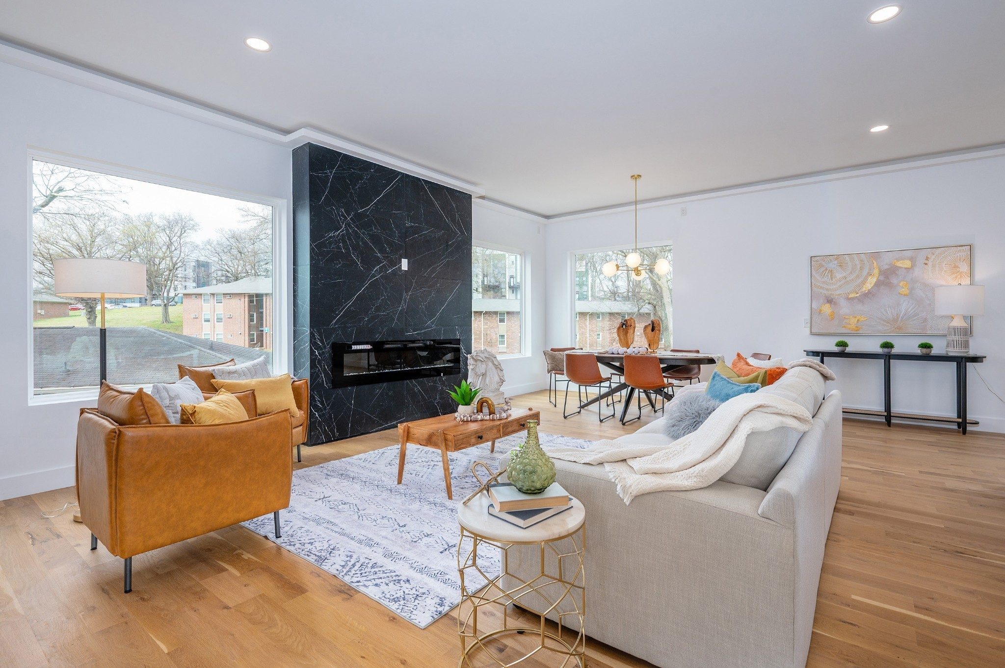 Open living and dining area with light wood floors and a black stone fireplace wall at 1001 Glenview Drive in East Nashville