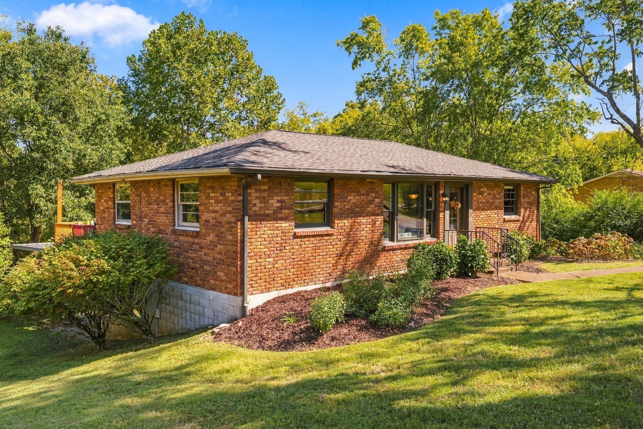 Front exterior of 1829 Willow Springs Drive, a red brick 1962 ranch with a low hip roof, front windows, and mature trees on a large lawn, one of the East Nashville homes for sale in Nashville