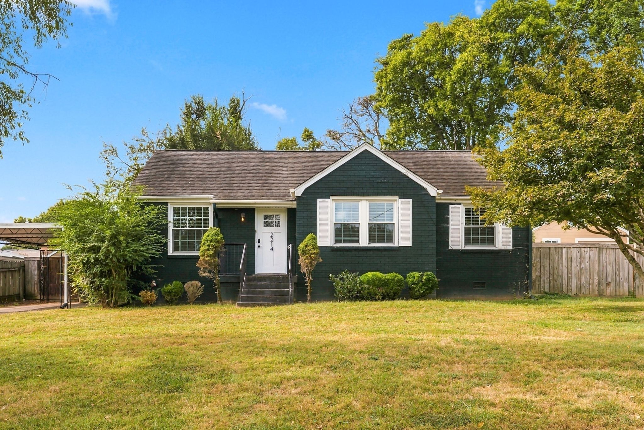 Front exterior of 2214 Fernwood Drive, a dark green painted 1950 cottage with white trim, a front gable, and a wide front lawn, one of the East Nashville homes for sale in Nashville