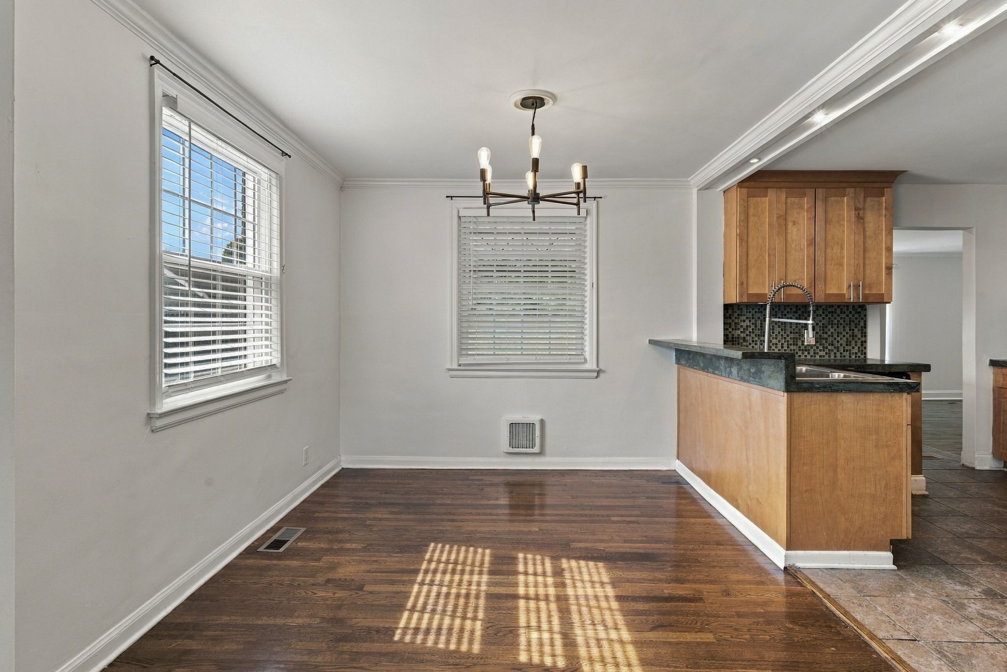 Dining area with a chandelier, hardwood floors, and the updated kitchen beyond at 2214 Fernwood Drive in East Nashville