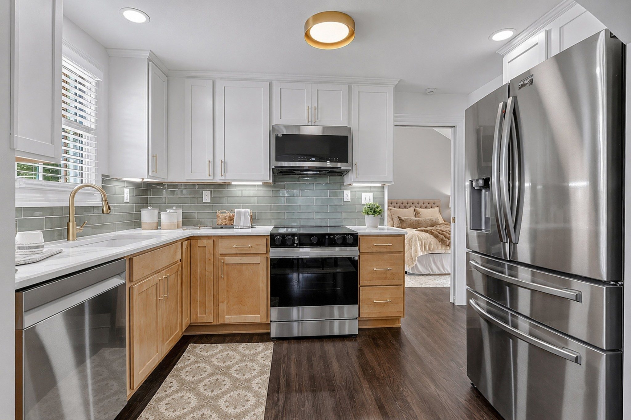 Renovated kitchen with white upper cabinets, natural wood lower cabinets, a green tile backsplash, and stainless appliances at 2217 Pinewood Road in East Nashville