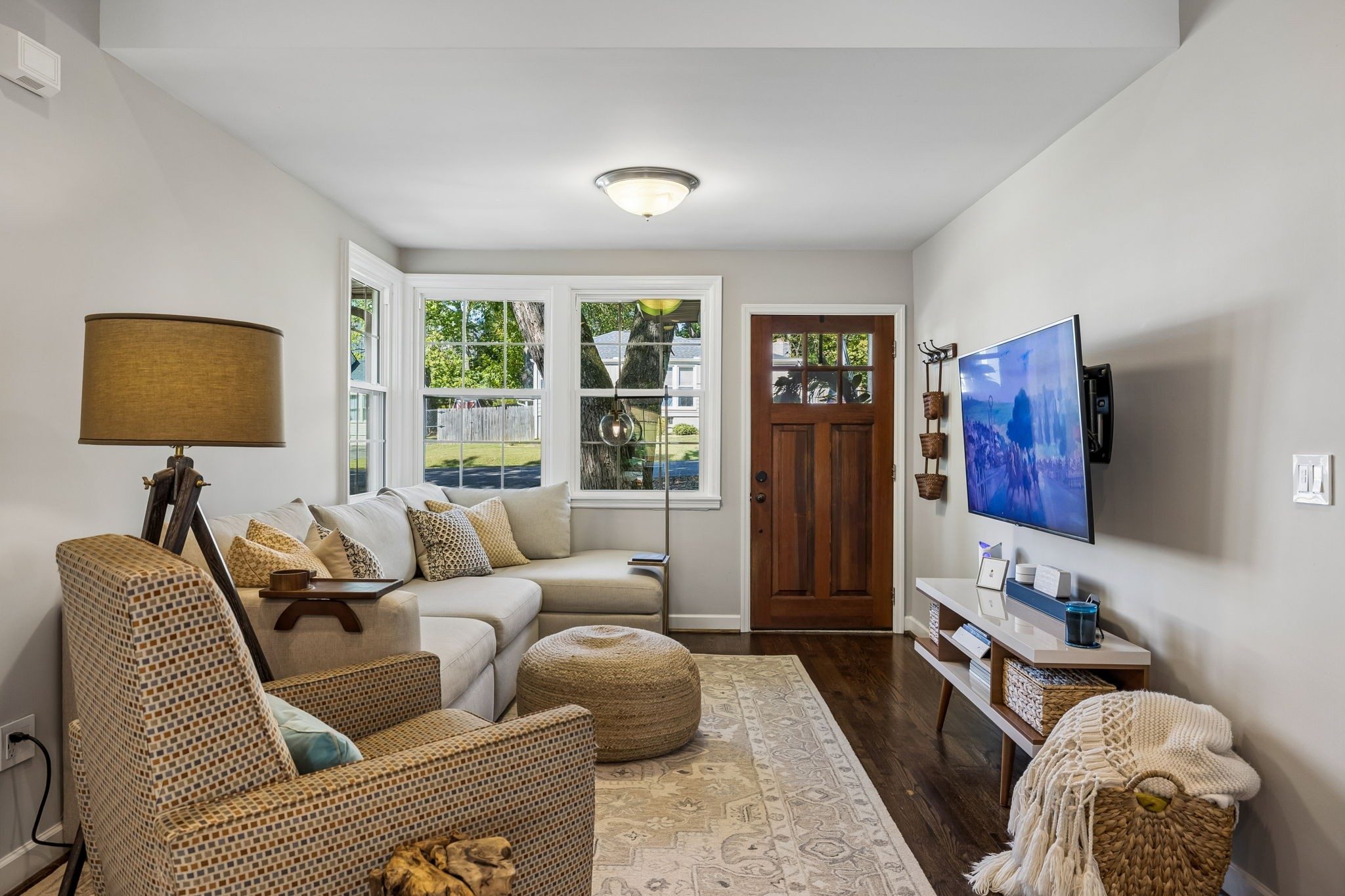 Living room with dark wood floors, a sectional sofa, and a wood front door at 3812 Inglewood Circle North in East Nashville