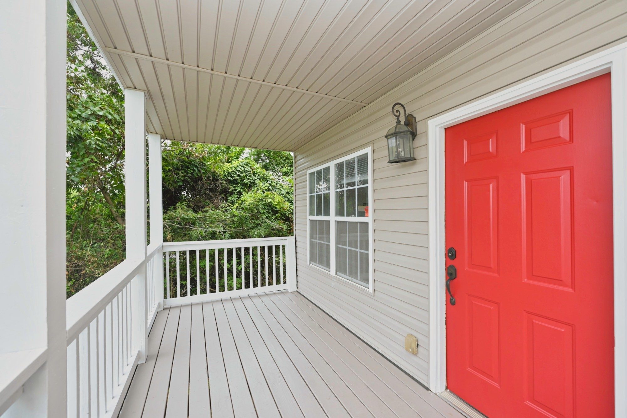 Covered front porch with white railings, light siding, and a red front door at 503 Ben Allen Road in East Nashville