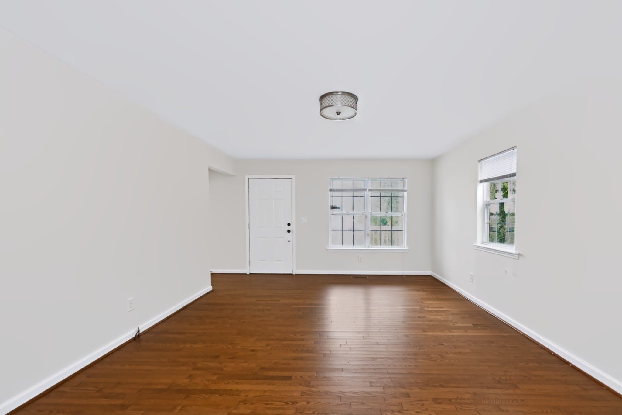 Empty room with dark wood floors, white walls, and windows on two sides at 503 Ben Allen Road in East Nashville