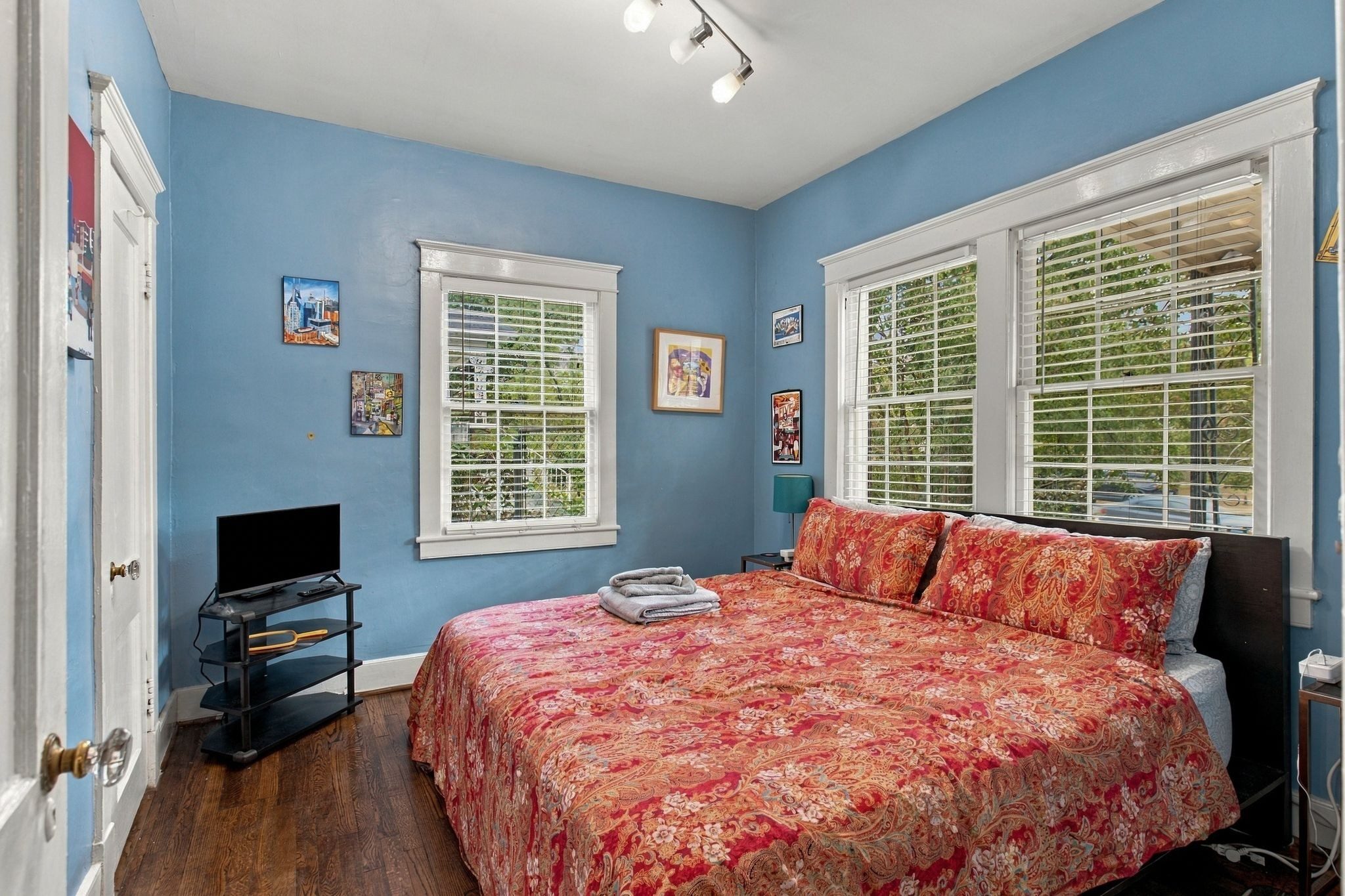 Bedroom with blue walls, hardwood floors, and windows on two sides at 711 Shelby Avenue in East Nashville